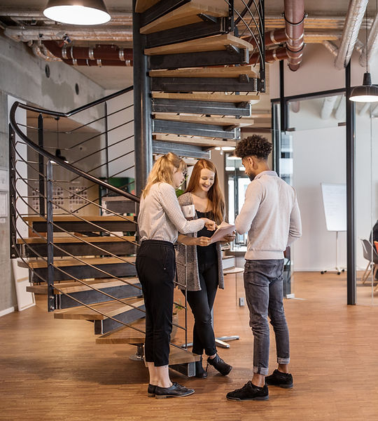 Modern coworking office with spiral staircase, collaborative team discussion, casual lounge area, and glass conference room w