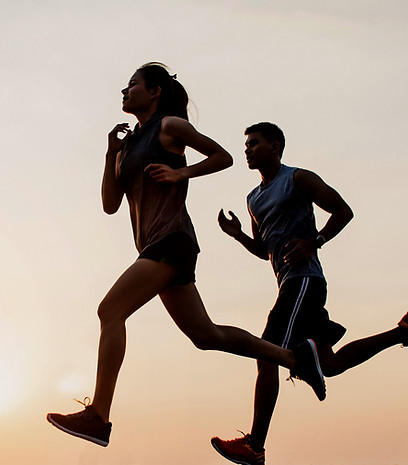 Silhouette of a man and a women running outside at sunset