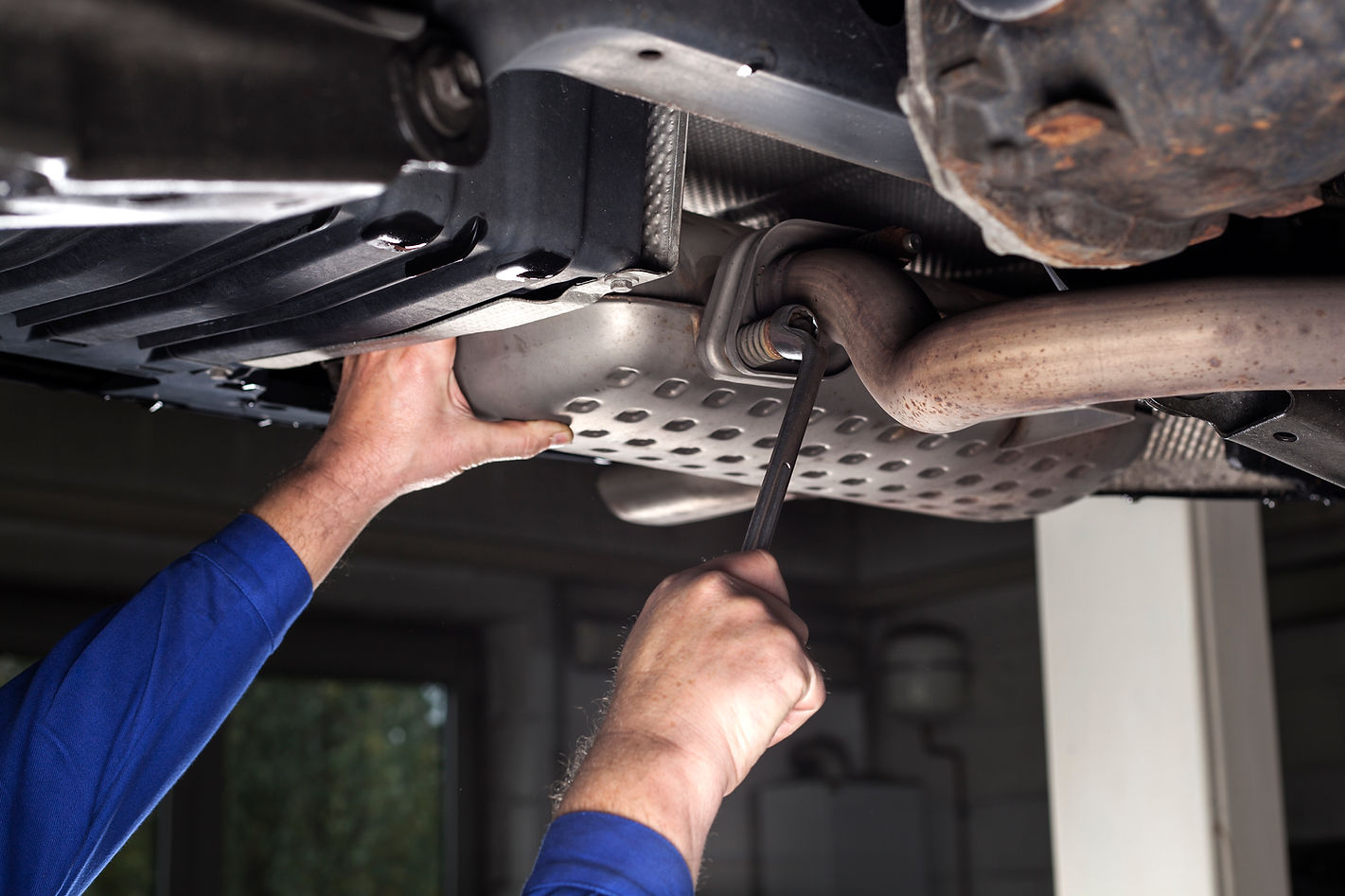 Mechanic is fixing the exhaust system of a modern car