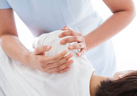 An osteopath assessing a person's posture and movement before beginning hands-on treatment in a clinical setting.