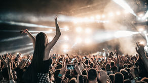 Fans cheering at a live concert with bright stage lights