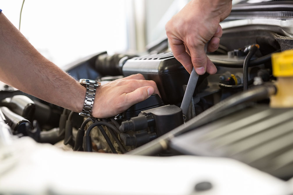 Close-up of a person using a wrench on engine parts under the hood