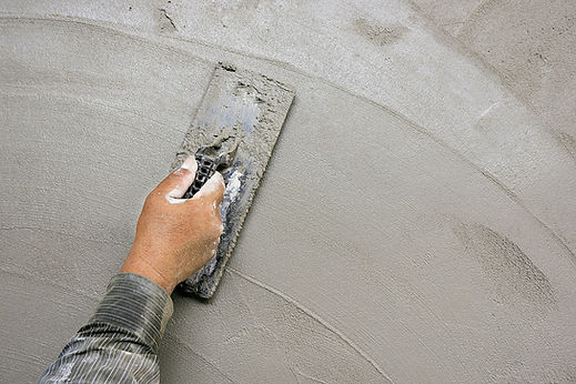 Close-up view of a trade professional skimming a wall surface with a steel hand trowel