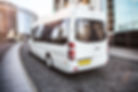 White mini bus moves down the street in the center of the city