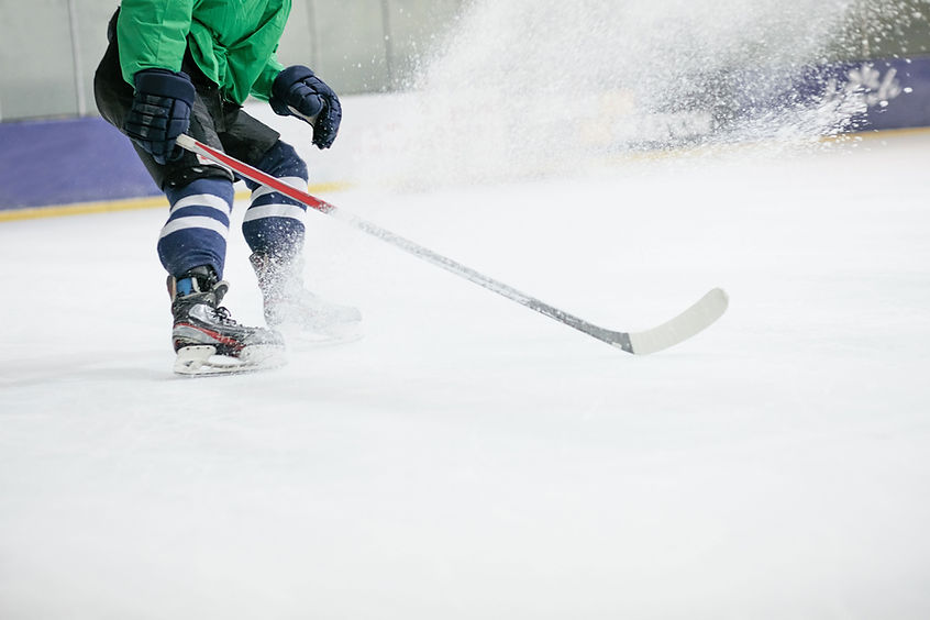 Hockey player on ice spraying ice with stick