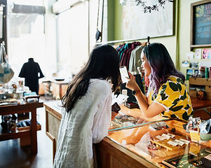 Shop worker showing client information on smart phone while checking out at counter