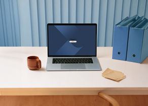 Laptop on a desk with a coffee cup and binders