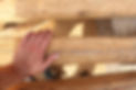 close-up image of a person's hand while examining damaged wood