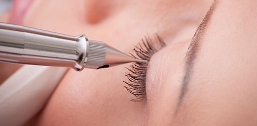Gros plan sur un oeil fermé. La pointe d'un dermographe est posée sur le bord de la paupière supérieure afin de procéder à un eye liner