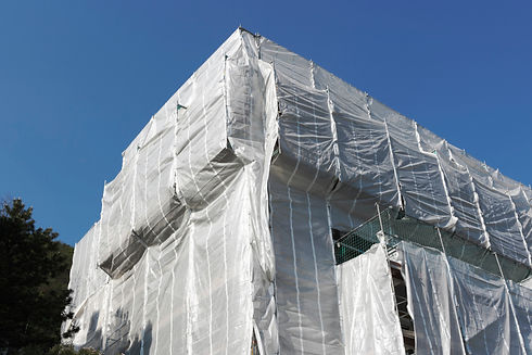 Temporary weather protection system featuring white sheeting over a scaffolding structure