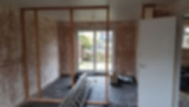 An unfinished room with exposed wooden framing, dirty walls, and a ladder