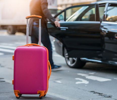 People taking taxi from an airport and loading carry-on luggage bag to the car.