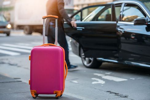 People taking taxi from an airport and loading carry-on luggage bag to the car