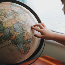 Child pointing to a country on a globe signifying relocation through immigration.