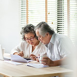 An old couple is calculating their budget, showing that CapStacked provides a complete wealth strategy.