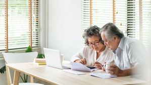 an Asian couple sitting at a table looking at a calculator