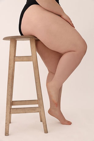 Plus size larger bodied person sitting on a stool being authentically themselves