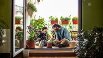 Father and son sitting in their garden balcony having a good time, laughing while taking care of plants