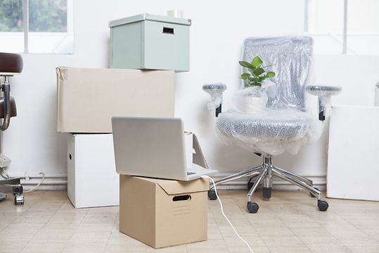 Stack of cardboard boxes, wrapped swivel chair and a notebook in an office