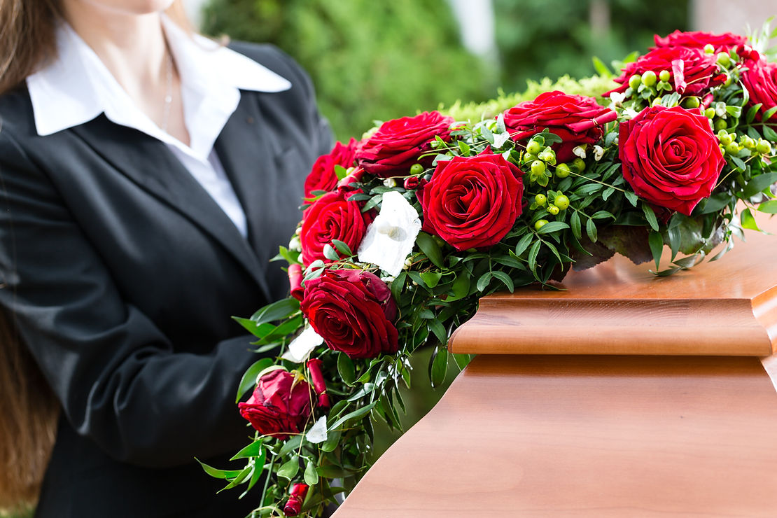 Mourning woman on funeral with red rose standing at casket
