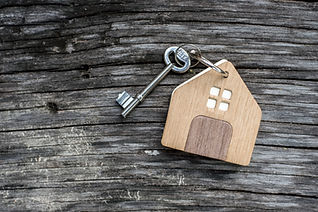 Small wooden model house with keys on a rustic grey wooden surface