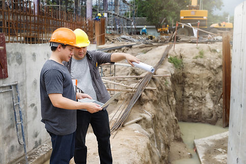 Two male engineers looking information on Imac at a construction site