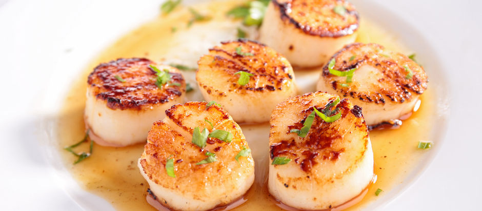 Golden-brown seared scallops served on a white plate with a drizzle of butter and a sprinkle of sea salt, inspired by the coastal simplicity of Pass-a-Grille, Florida
