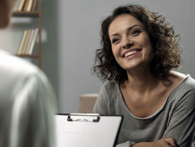 Smiling woman talking with a psychologist during a therapy session at Retrieve Mind Poly Clinic in Dubai.