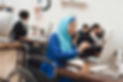 Woman wearing a hijab sitting in wheelchair working on a computer while talking on the phone.