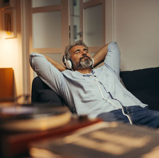 man enjoying music in headphone while laying on sofa