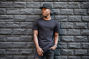 A person in a black t-shirt stands in front of a textured stone wall, with overlay text 'Closer Lives Emporium' in bold yellow, with 'travel time' in bold white text beneath it.