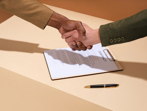 Buyer and agent shaking hands over a purchase contract while buying a home in the Antelope Valley