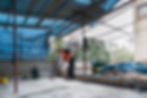 A construction worker sweeps debris under a blue tarp