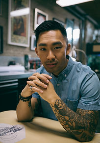 Asian man with tattoos and hands clasped