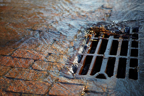 Water flowing over a street drain with debris