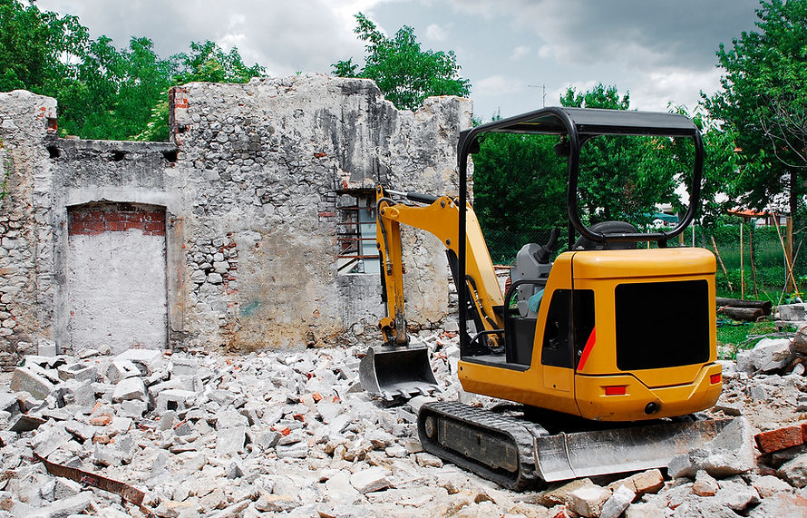 A compact excavator on a small domestic building site where a block building