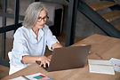 Bejaarde vrouw die aan laptop werkt