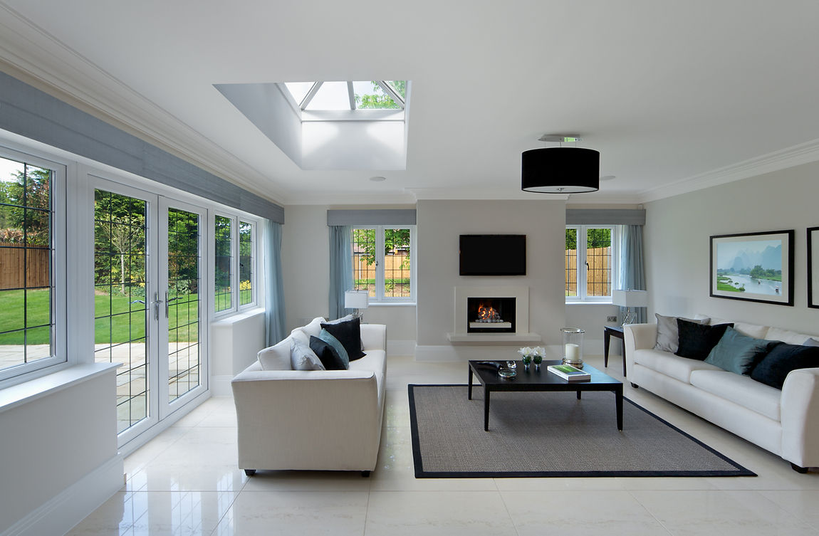A modern living room with large windows, skylight, and garden view