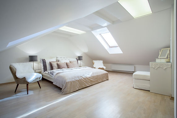 Cozy attic bedroom with soft lighting, a skylight, and neutral tones