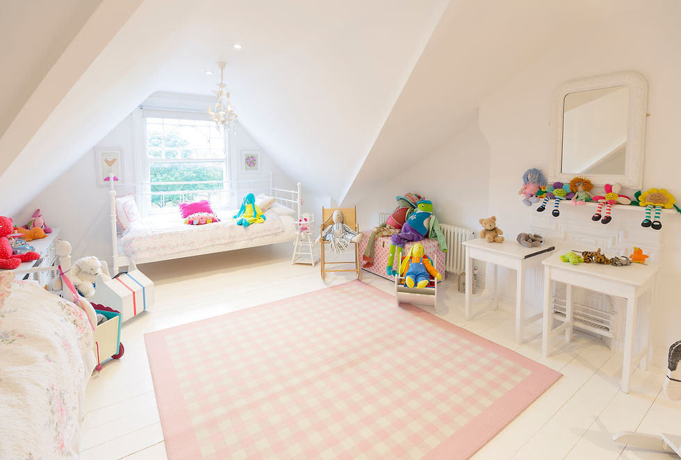 A spacious, brightly lit children's bedroom with two beds, a pink rug, and toys.