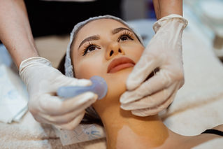 Beautiful young woman lying down in the beauty clinic and having a facial cupping massage
