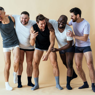 A group of men laughing together in a studio setting, illustrating open conversations about men's sexual health.