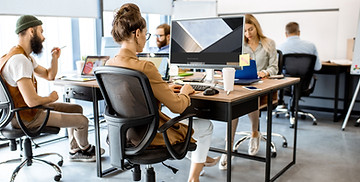 Un bureau avec 5 personnes travaillant sur des ordinateurs