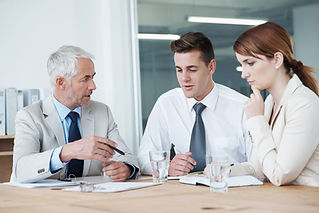 Three business professionals reviewing paperwork together around an office desk