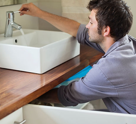 An Aquaflame plumber repairing a bathroom sink.