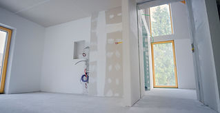 Unfinished room with drywall patches, exposed wiring, and a large window