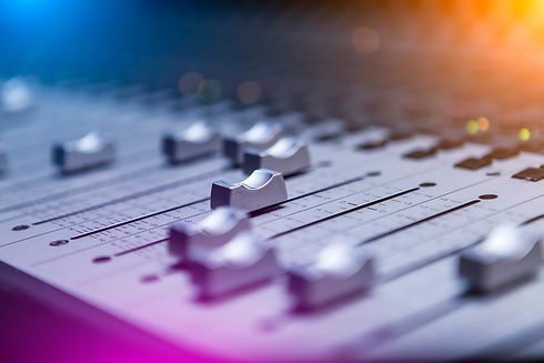 Close-up of a sound mixing board with various sliders and knobs