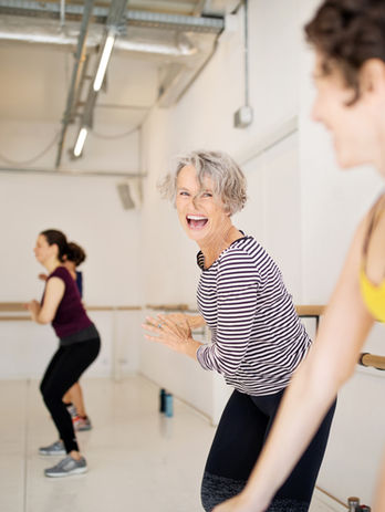 Women of different ages doing aerobics together with a female senior citizen in the middle of the picture.