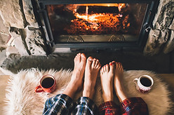 Romantic couple with Feet by the Fire in their pajamas with coffee in a secluded cabin in the Smoky Mountains