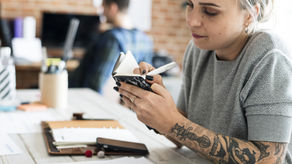 Woman thoughtfully writing in a notebook, representing the act of brainstorming and documenting ideas for a side hustle.